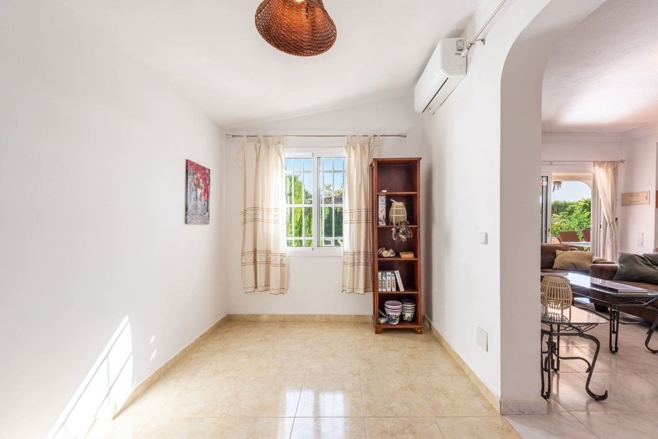 Salón-comedor abierto con dos sofás, dos mesas auxiliares y lámpara de techo