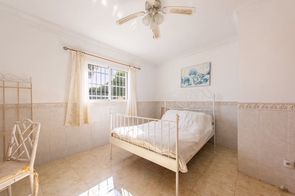 Dormitorio con cama individual blanca, mesilla blanca y cuadro decorativo sobre la cama