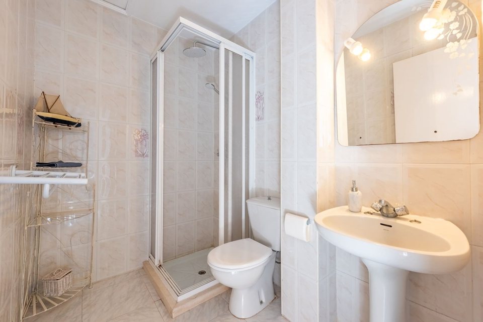 Baño con plato de ducha de esquina, lavabo sobre mueble blanco y espejo grande