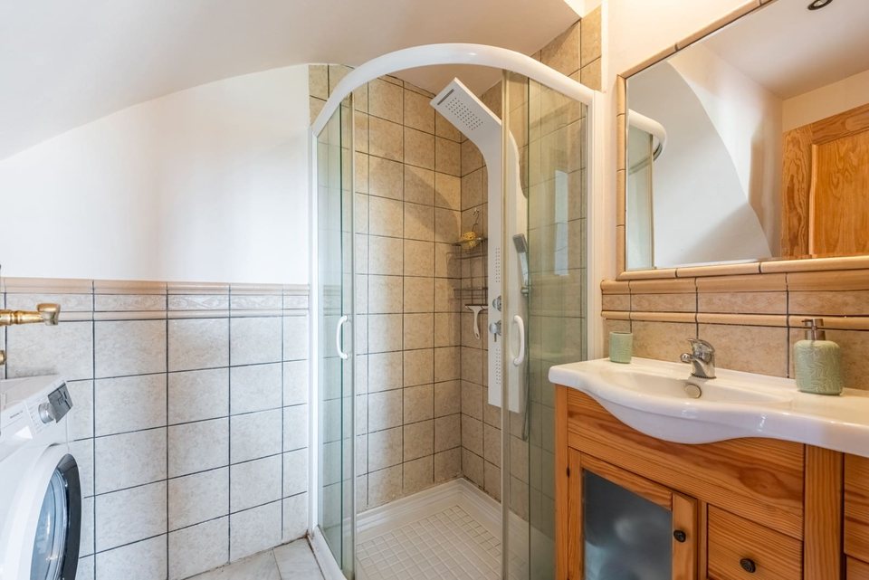 Baño con ventana azul, lavabo sobre encimera, espejo y sanitarios blancos