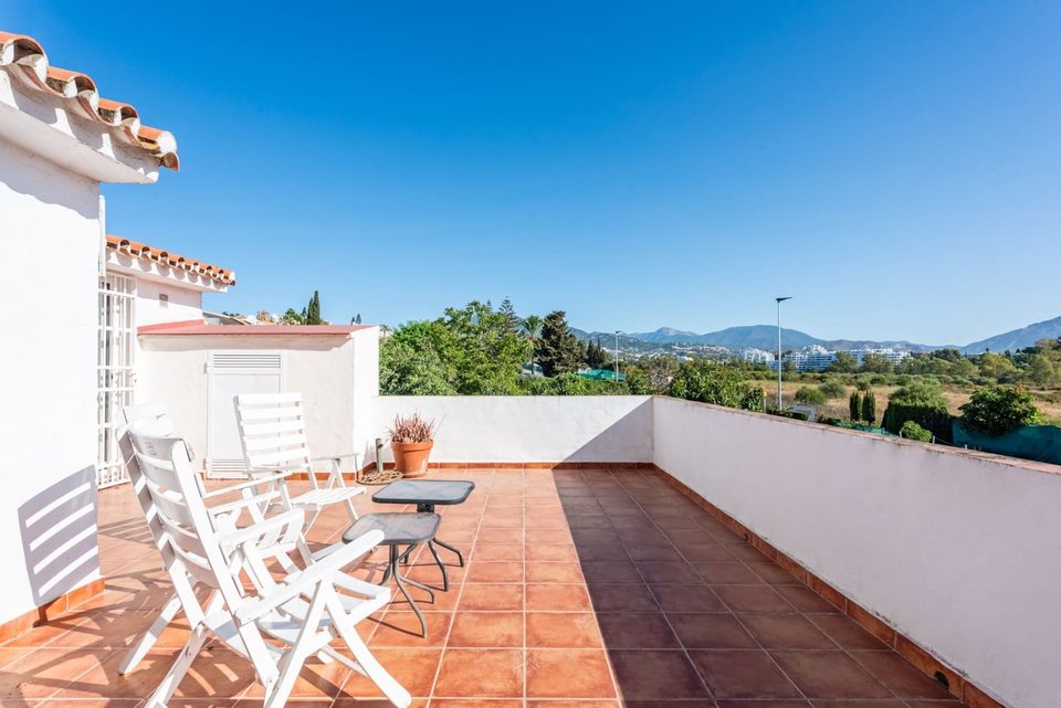 Terraza de la primera planta con barandilla blanca, suelo de barro y zona de descanso