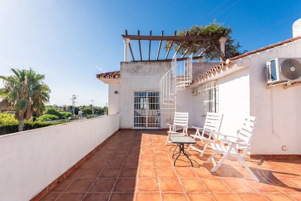 Terraza con pérgola superior, tumbonas blancas y vistas al paisaje y la costa