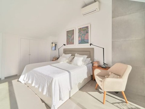 Dormitorio abuhardillado del chalet — planta ático con techo inclinado, salida a terraza privada y vistas al mar