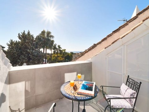 Terraza privada del chalet — mesa, dos sillas y palmeras con vistas a los tejados mediterráneos del complejo Montepiedra