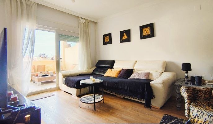 Salón con sofá crema y acceso a la terraza