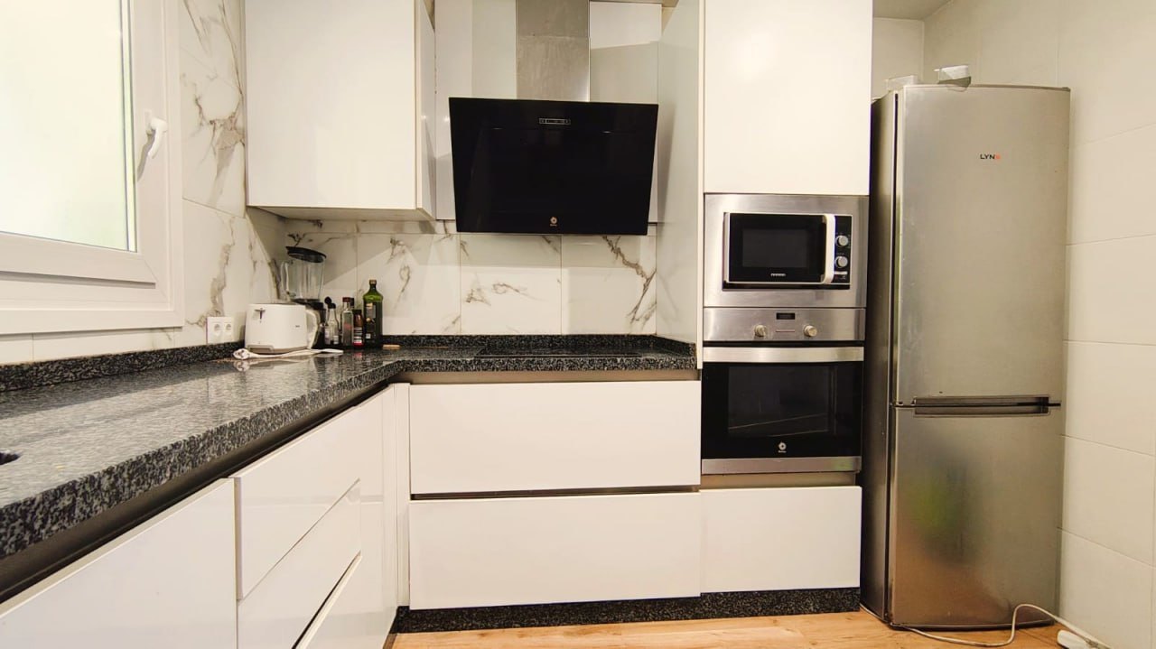 Cocina con encimera de granito negro y electrodomésticos integrados