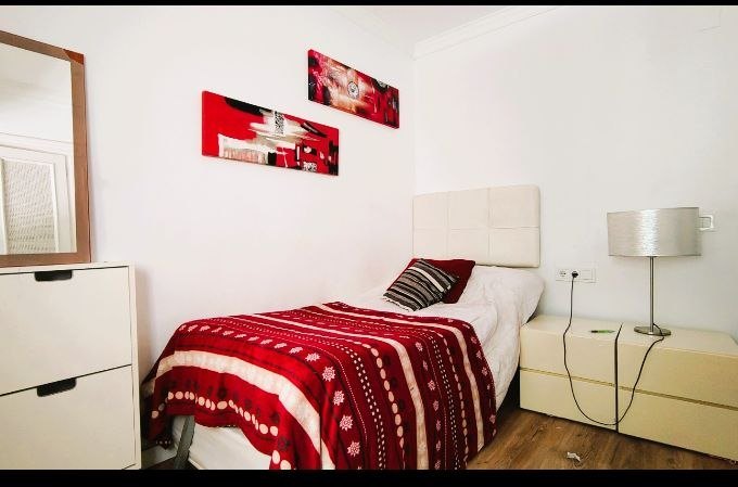 Dormitorio con colcha roja y cuadros