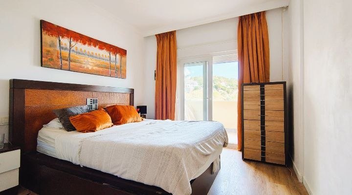 Dormitorio principal con cabecero de madera y cortinas naranja