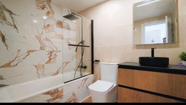 Baño con bañera y lavabo sobre encimera de madera