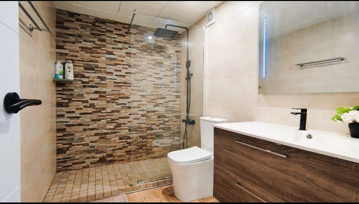 Baño con mosaico en pared de piedra y bañera