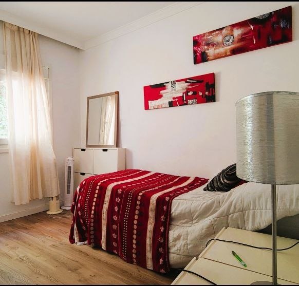 Dormitorio con colcha roja y cuadros rojos, otra vista