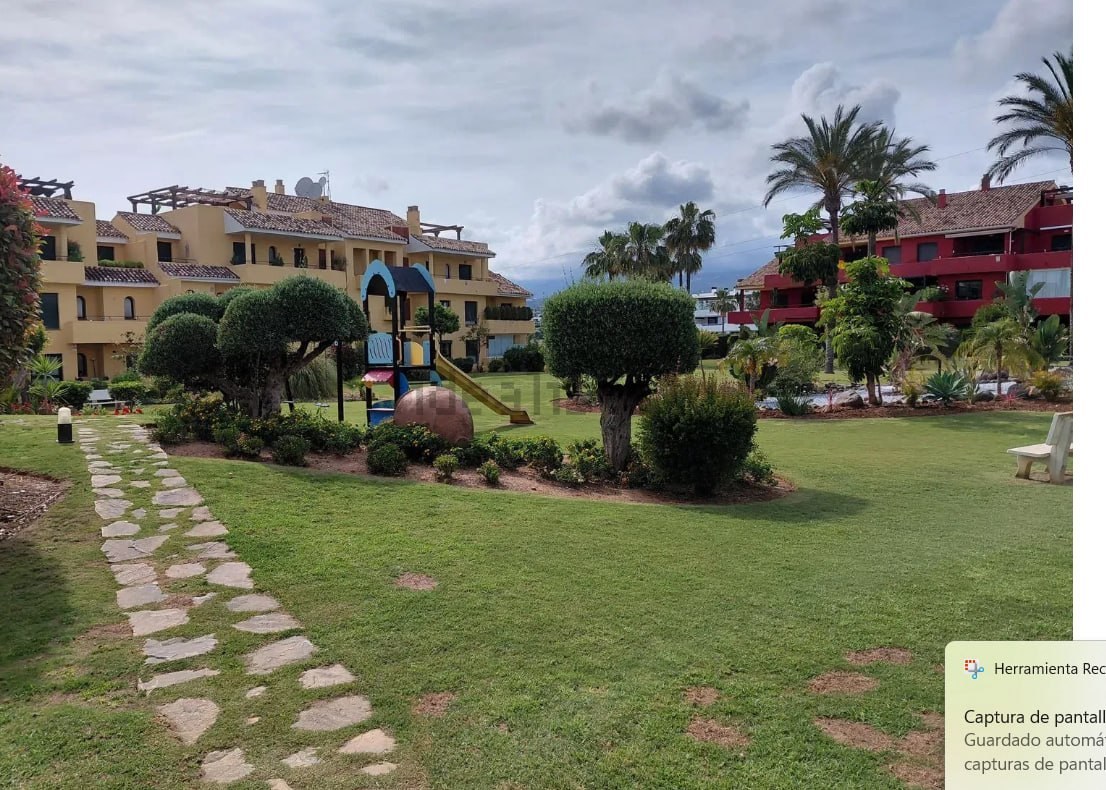 Zonas comunes con jardín, palmeras y camino empedrado entre las viviendas del conjunto